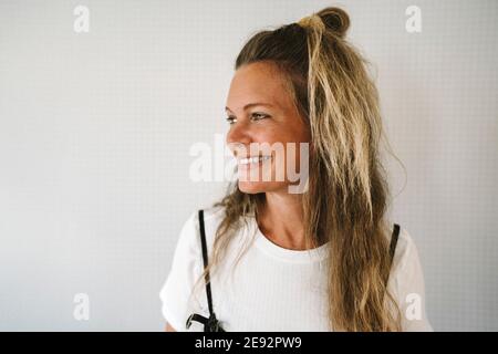 Lächelnde reife Frau, die gegen die Wand schaut Stockfoto