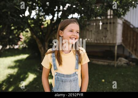 Lächelndes Mädchen, das wegschaut, während es im Hinterhof steht Stockfoto