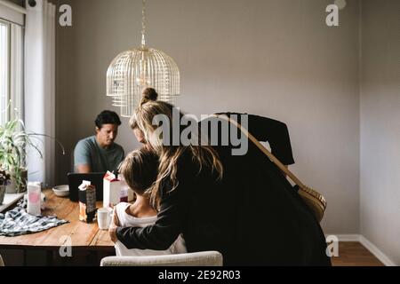 Mutter küsst Sohn über Esstisch zu Hause Stockfoto