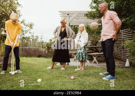 Pre-Jugendlicher Junge spielt Polo mit Familie im Hinterhof Stockfoto