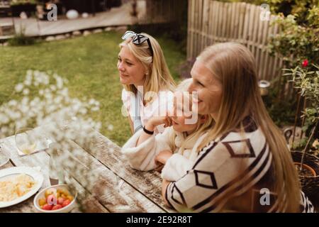 Lächelnde Mutter und Töchter sitzen im Hinterhof Stockfoto