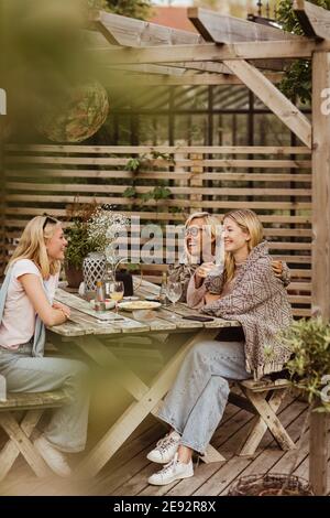 Freundinnen verbringen Zeit mit Großmutter am Tisch im Rücken Hof Stockfoto