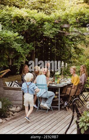 Lächelnde Familie, die den Jungen beim Abendessen ansieht Hinterhof Stockfoto