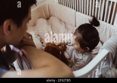 Vater schaut auf Baby Sohn spielen in Krippe zu Hause Stockfoto