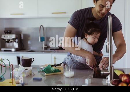 Vater waschen Baby Sohn die Hand unter Waschbecken in der Küche Stockfoto