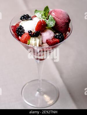 Eis servieren in einem Glas mit verschiedenen Beeren Stockfoto