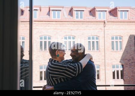 Heterosexuelles Paar umarmt sich gegenseitig auf dem Balkon Stockfoto
