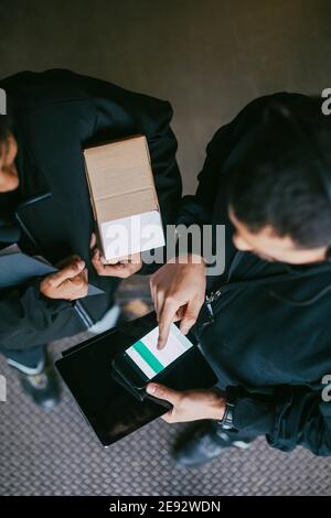 Weibliche und männliche Arbeiter, die im Lager ein Mobiltelefon benutzen Stockfoto