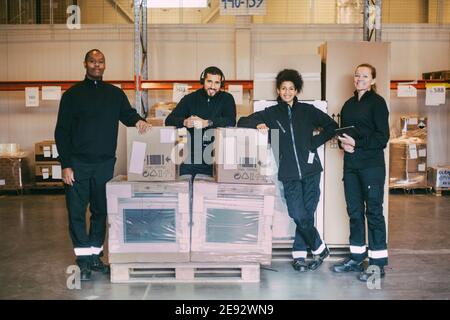 Portrait von lächelnden Handarbeitern, die mit Box-Containern stehen Logistiklager Stockfoto