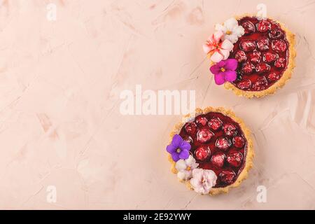 Frühling hausgemachte Mini-Kuchen mit Beeren mit Blumen geschmückt Stockfoto