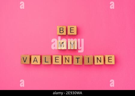 Holzwürfel mit der Phrase Be My Valentine auf einem leeren bunten rosa Hintergrund. Worte der Liebe sind aus Briefen aus Holz für Valentinstag und für Ihre Freundin, Freund, Frau, Mann Gruß romantische Postkarte. Flach liegend, Draufsicht Stockfoto