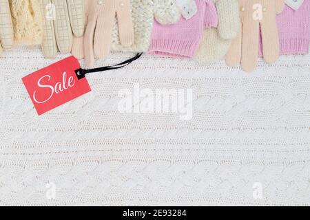 Winter flach Lay mit Fäustlingen, Handschuhe und Sale-Tag auf weißem gestrickten Hintergrund. Stockfoto