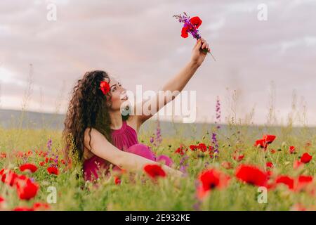 Junge entzückende Mädchen trägt Mohn in den Haaren und hält Ein Strauß wilder Blumen Stockfoto