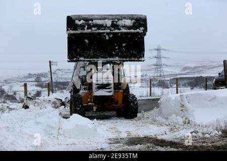 Littleborough, Großbritannien. Februar 2021. Der Schneefall hat viele Nebenstraßen im Littleborough-Gebiet blockiert. Ein Traktorfahrer kam zur Rettung des Personals, das versuchte, ein Tierschutzgebiet zu erreichen, das von karitativen Tieren in Not geführt wird. Blackstone Edge, Littleborough, Lancashire, Großbritannien. Kredit: Barbara Cook/Alamy Live Nachrichten Stockfoto