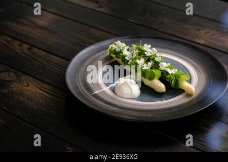 Gericht gekochten weißen Spargel plattiert und mit Weiß dekoriert Blumen und Sahne auf der Seite in einem Restaurant Stockfoto
