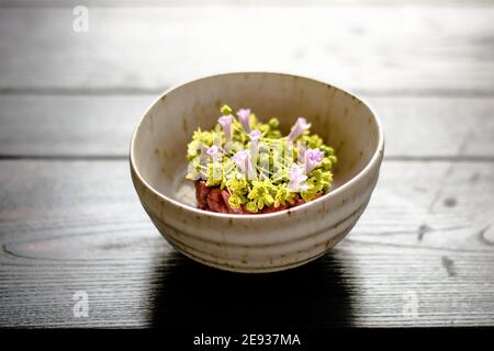 Rote Fleischtartare dekoriert und mit Blumen und Garten überzogen Grün Stockfoto