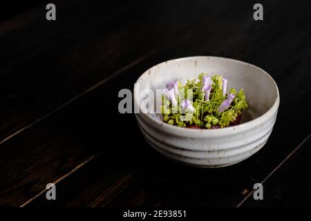 Rote Fleischtartare dekoriert und mit Blumen und Garten überzogen Grün Stockfoto