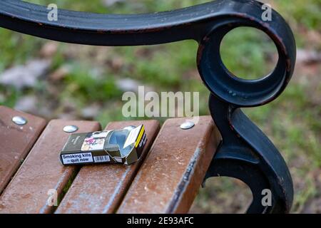 Leere Zigarettenschachtel von Rothmans Blue, die auf einer Parkbank zurückgelassen wurde, um sie zu banning oder mit nach Hause zu nehmen, Abington Park, Northapton, England, Großbritannien. Stockfoto