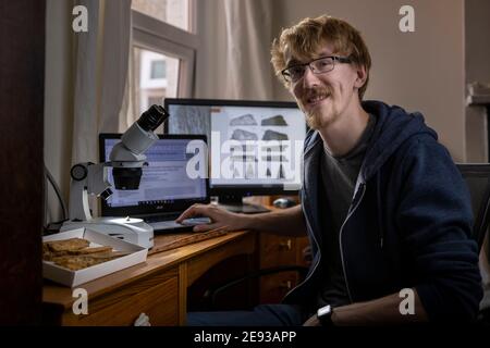 Doktorand Roy Smith 26, in seinem Haus in Portsmouth mit einem winzigen Fragment versteinerten Knochen, von dem er glaubt, dass er eine neue Art von Dinosaurier ist, der zahnlose Stockfoto