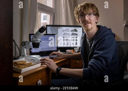 Doktorand Roy Smith 26, in seinem Haus in Portsmouth mit einem winzigen Fragment versteinerten Knochen, von dem er glaubt, dass er eine neue Art von Dinosaurier ist, der zahnlose Stockfoto