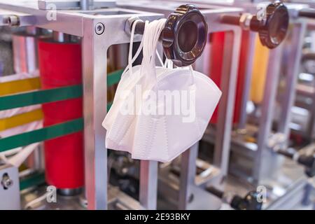 Medizinische Masken auf der automatischen Maschine für die Herstellung. Coronavirus und Covid-19-Schutz Stockfoto