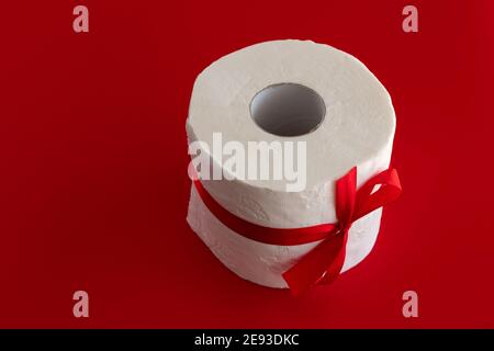 Rolle Toilettenpapier mit rotem Klebeband auf rotem Hintergrund gewickelt. Das Konzept von Valentinstag und Coronavirus. Romantisches Urlaubsmockup. Liebeskonzept. Stockfoto