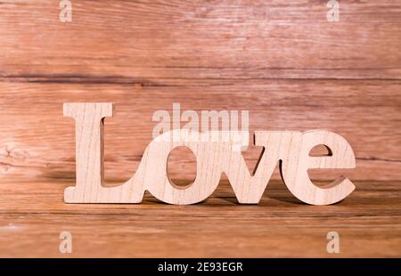 Holzbuchstaben bilden Wort Liebe geschrieben am hölzernen Hintergrund Stockfoto