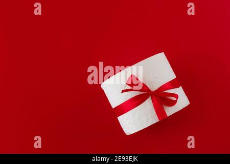 Rolle Toilettenpapier mit rotem Klebeband auf rotem Hintergrund gewickelt. Das Konzept von Valentinstag und Coronavirus. Romantisches Urlaubsmockup. Liebeskonzept. Stockfoto