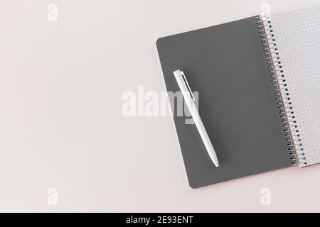 Spiral geöffnetes Notizbuch mit grauem Blatt und weißem Stift. Layout und flache Lage mit Platz für Text isoliert auf weißem Hintergrund. Zurück zur Schule. Draufsicht, Stockfoto