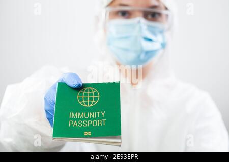 Medical UK Healthcare Security Officer Arbeiter in persönliche Schutzausrüstung Halten grüne Immunität Pass-ID-Karte, risikofreies Zertifikat Dokument Stockfoto