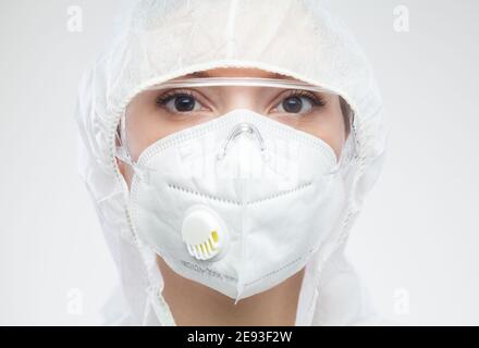 Kopfbild Porträt der kaukasischen Frau UK Labor Tech Scientist Frau, NHS Arzt oder Krankenschwester tragen PPE Gesichtsmaske, Overall Anzug und Schutz Brillenbrille Stockfoto