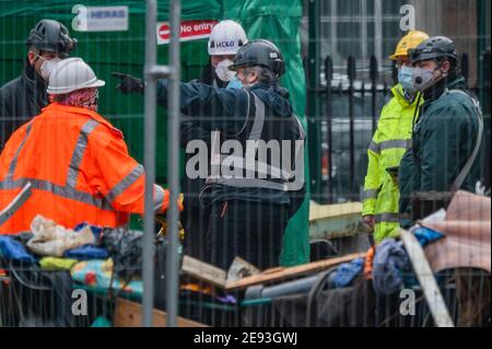 London, Großbritannien. Februar 2021. Bailifs diskutieren Taktiken außerhalb des Tunneleingangs - das Lager gegen das HS2-Aussterben wird weiterhin von den Gerichtsvollzieher (vom National Enforcement Team, NET, einer Tochtergesellschaft der High Court Enforcement Group) am Bahnhof Euston geräumt (um einen temporären Parkplatz zu schaffen). Alle oben genannten Demonstranten wurden geräumt, und es scheint nun eine Pause zu geben, bevor die Tunnel behandelt werden. Kredit: Guy Bell/Alamy Live Nachrichten Stockfoto