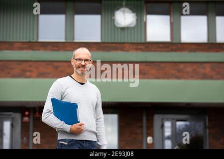 Lächelnder Lehrer vor der Schule Stockfoto