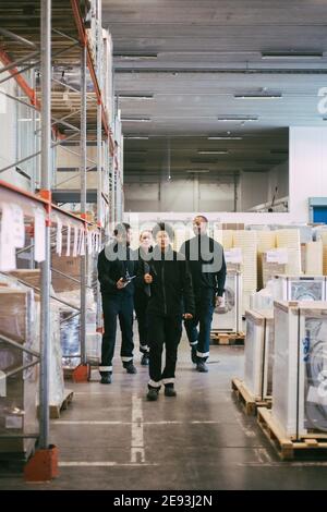 Weibliche und männliche Arbeiter diskutieren beim Gehen im Lager Stockfoto