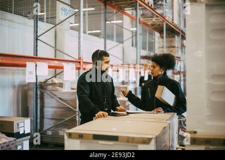 Weibliche Unternehmerin plant mit männlichen Kollegen während der Besprechung im Lager Stockfoto