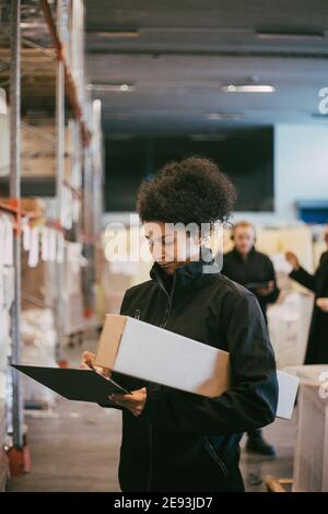 Geschäftsfrau beim Schreiben auf Zwischenablage im Distributionslager untersuchen Stockfoto