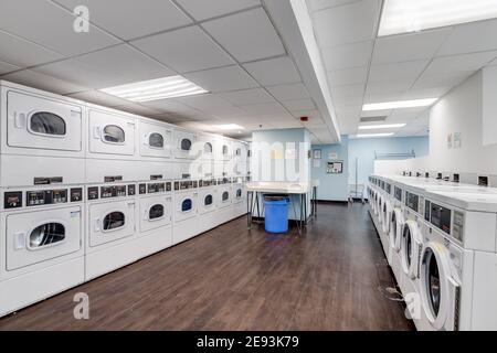 Ein Hochhauswaschsalon in der Innenstadt mit Schnellwaschmaschinen und Trocknern, die in Reihen angeordnet sind. Stockfoto