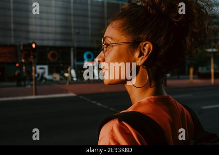 Geschäftsfrau, die während des Sonnenuntergangs in die Stadt schaut Stockfoto