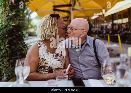 Ältere Paare küssen sich gegenseitig, während sie im Straßencafé sitzen Stockfoto