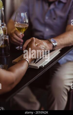 Zugeschnittenes Bild eines Paares, das die Hände über den Tisch im Café hält Stockfoto