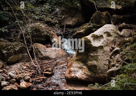 Ein kleiner Wasserfall, der über die Felsbrocken eines Baches fließt (Marken, Italien, Europa) Stockfoto