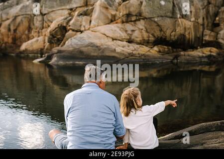 Vater und Tochter sitzen auf See Stockfoto