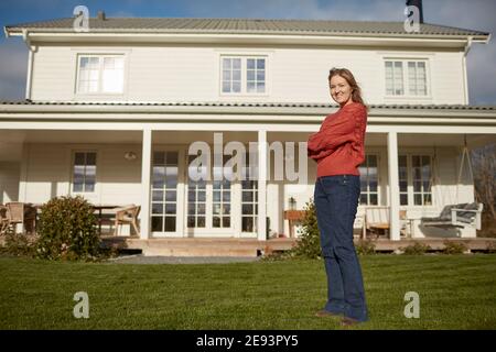 Junge Frau stand vor Haus Stockfoto