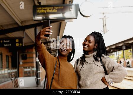 Lächelnde Freundinnen beim Selfie am Bahnhofsplatz Stockfoto