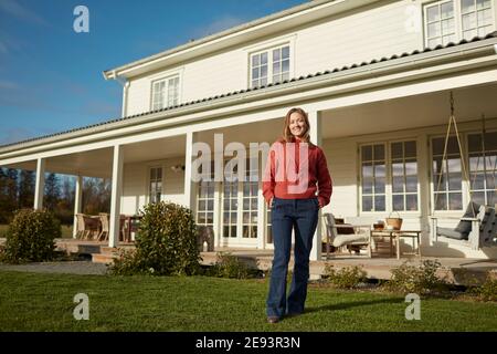 Junge Frau stand vor Haus Stockfoto
