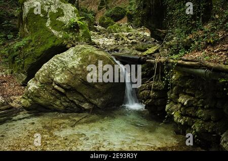 Ein kleiner Wasserfall, der über die Felsbrocken eines Baches fließt (Marken, Italien, Europa) Stockfoto