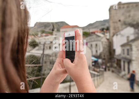 MOSTAR, BOSNIEN UND HERZEGOWINA - 15. Aug 2018: Eine Aufnahme des jungen Mädchens, das mit dem Telefon die historische Stadt Mostar in Bosnien und Herzegowina fotografiert Stockfoto