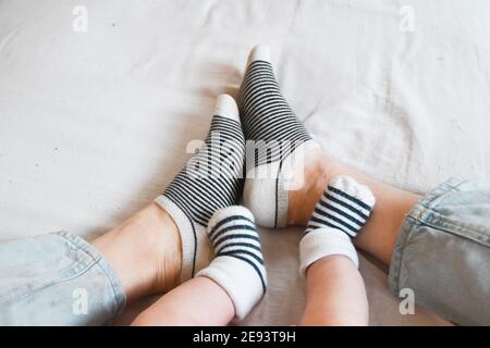 Die Füße von Mutter und Baby mit passenden Socken Stockfoto