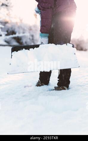 Nahaufnahme einer Person, die mit einer Schneeschaufel Schnee vom Bürgersteig räumte. Stockfoto