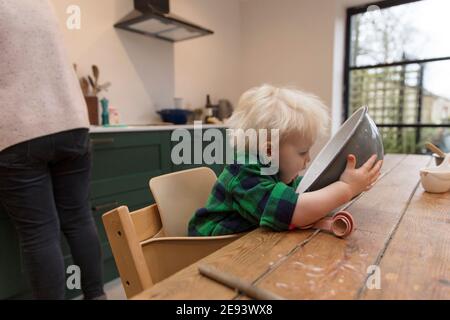 Ein Kleinkind hilft mit dem Backen in der Küche hält eine Rührschüssel. Stockfoto